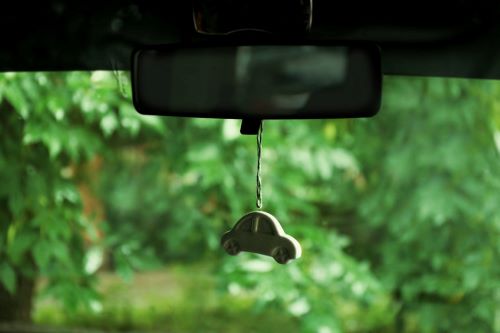 Ein grüner Duftspender hängt im Auto